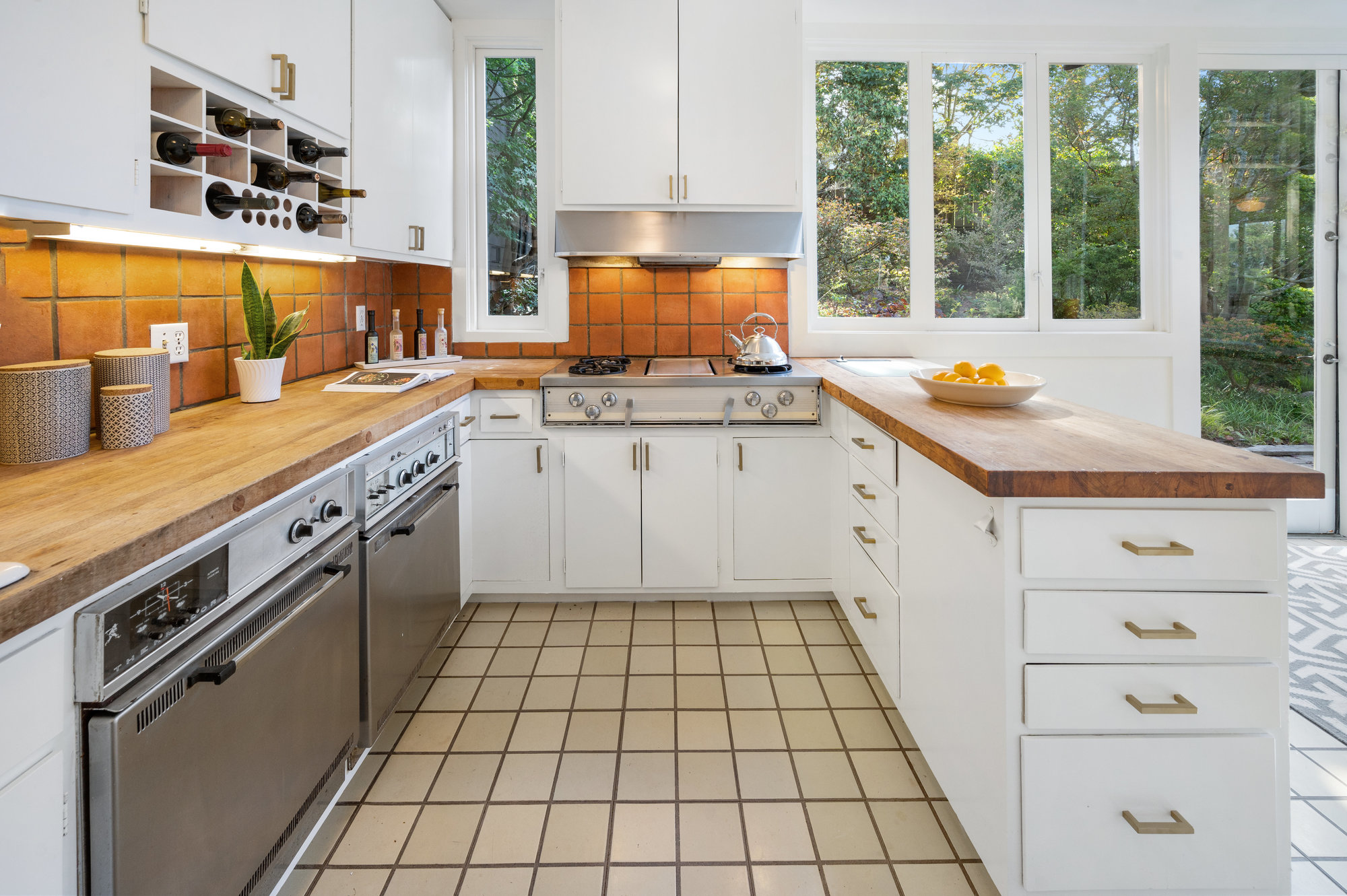 Property Photo: Kitchen with wooden counters and white cabinetry 
