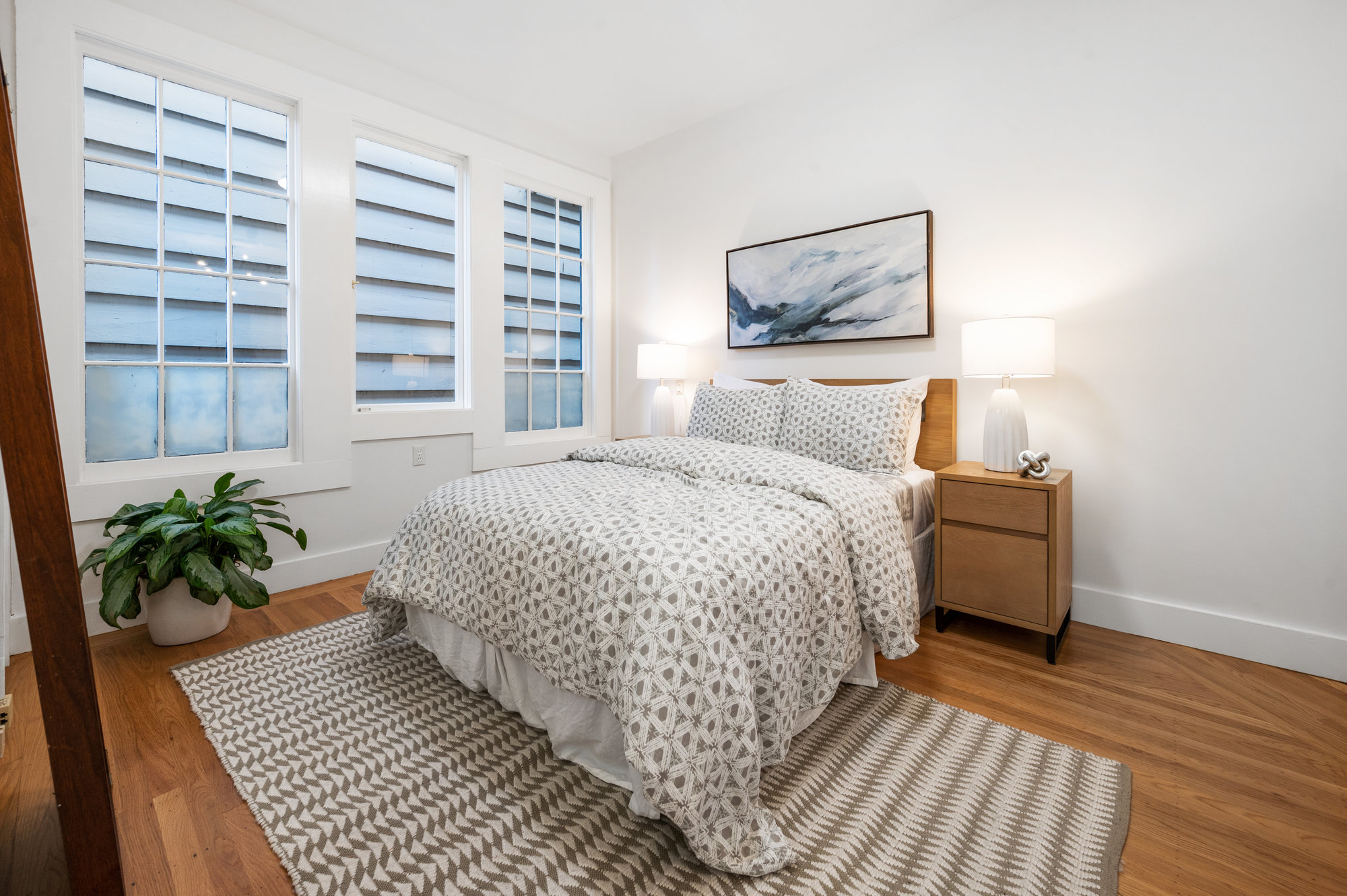 Property Photo: Bedroom four, featuring wood floors and large windows