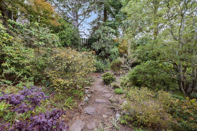 Property Thumbnail: View of a stone path leading through the gardens of 183 Edgewood Avenue in Cole Valley