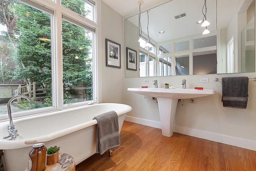 Property Photo: Alternative view of the bath, showing wood floors and a view of the lush yard beyond