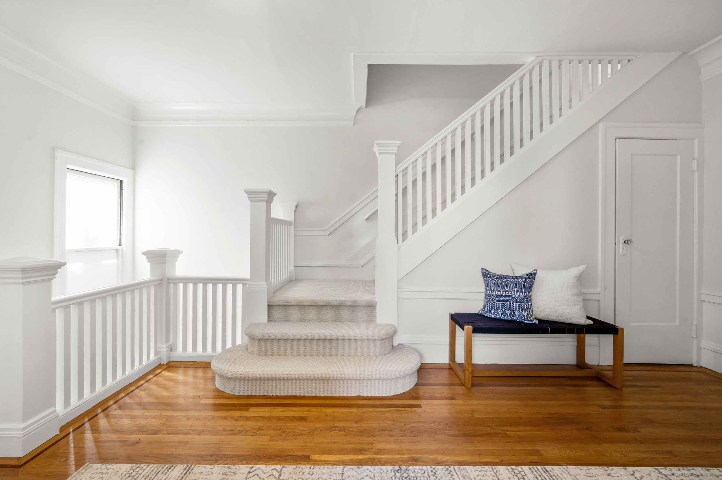 Property Photo: White wooden staircase leads upstairs 