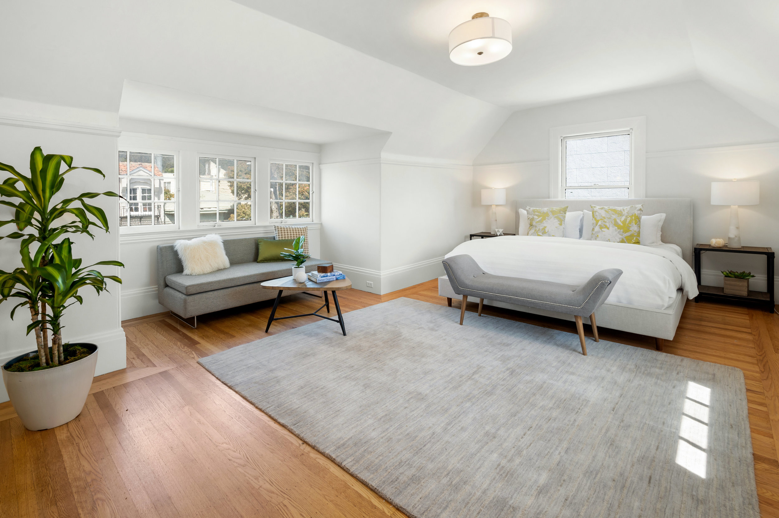 Property Photo: A luxury primary bedroom with wood floors and plenty of natural light