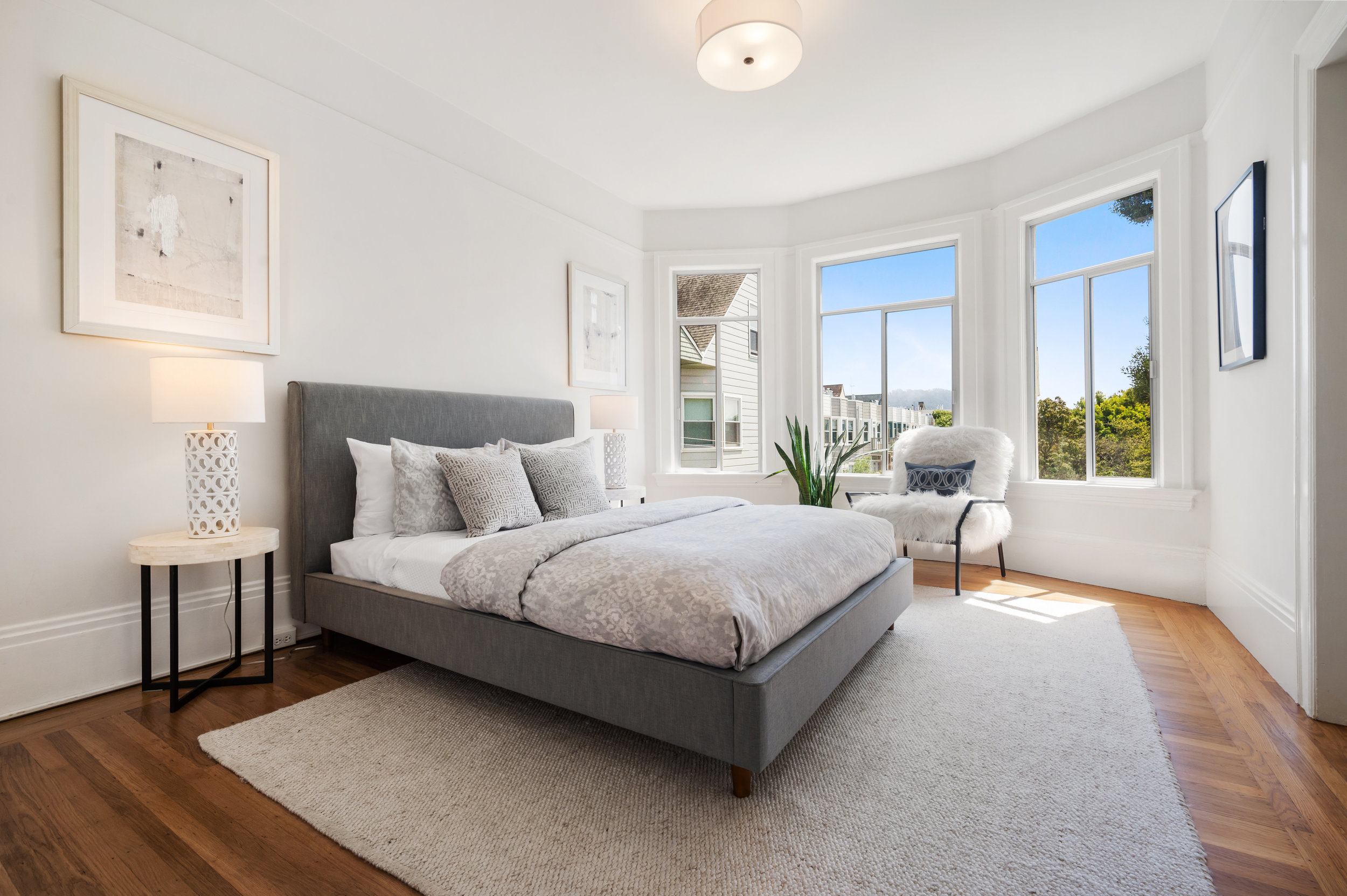 Property Photo: View of a second bedroom with bay windows and wood floors