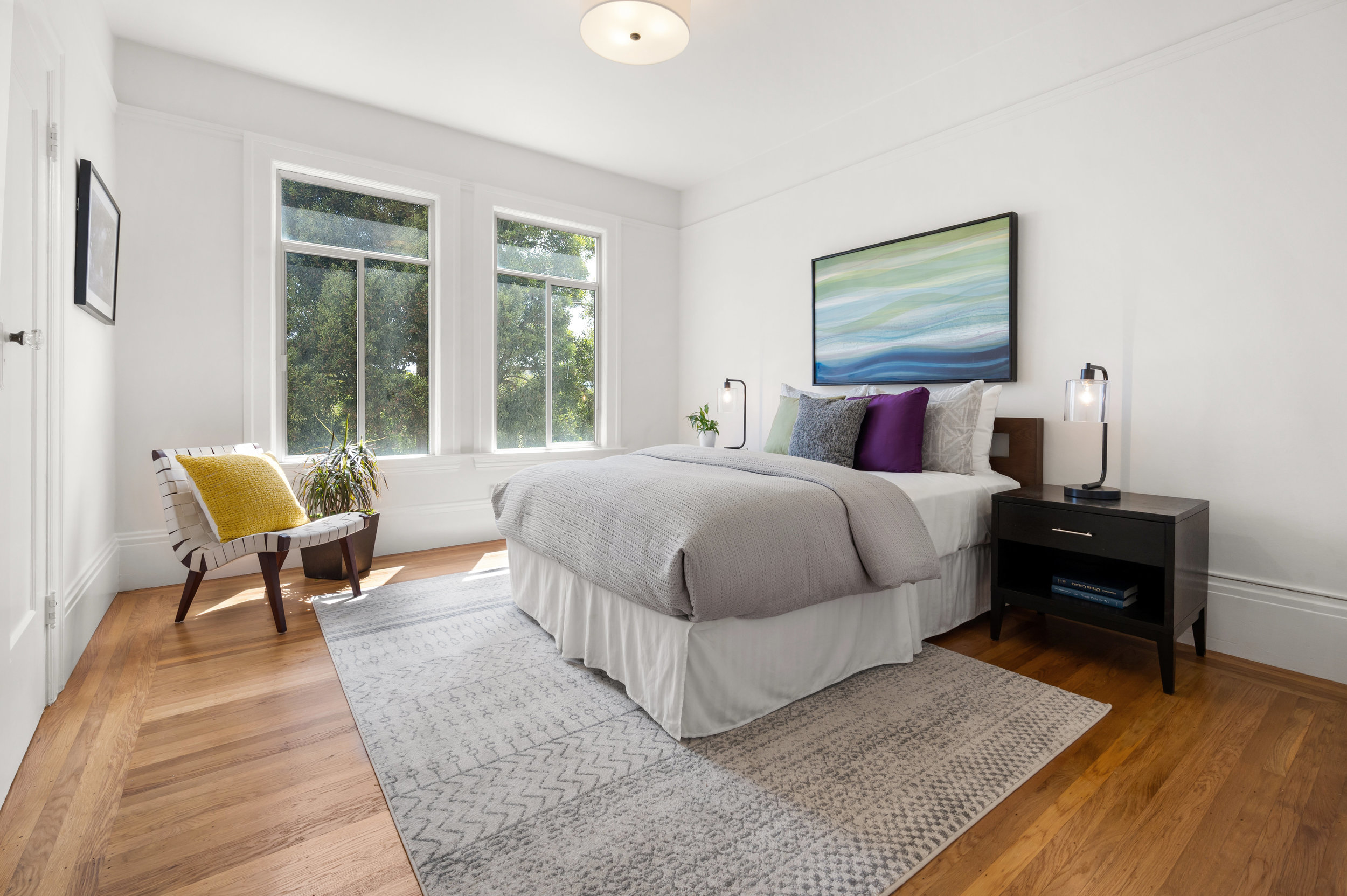 Property Photo: Bedroom three, featuring wood floors and two large windows