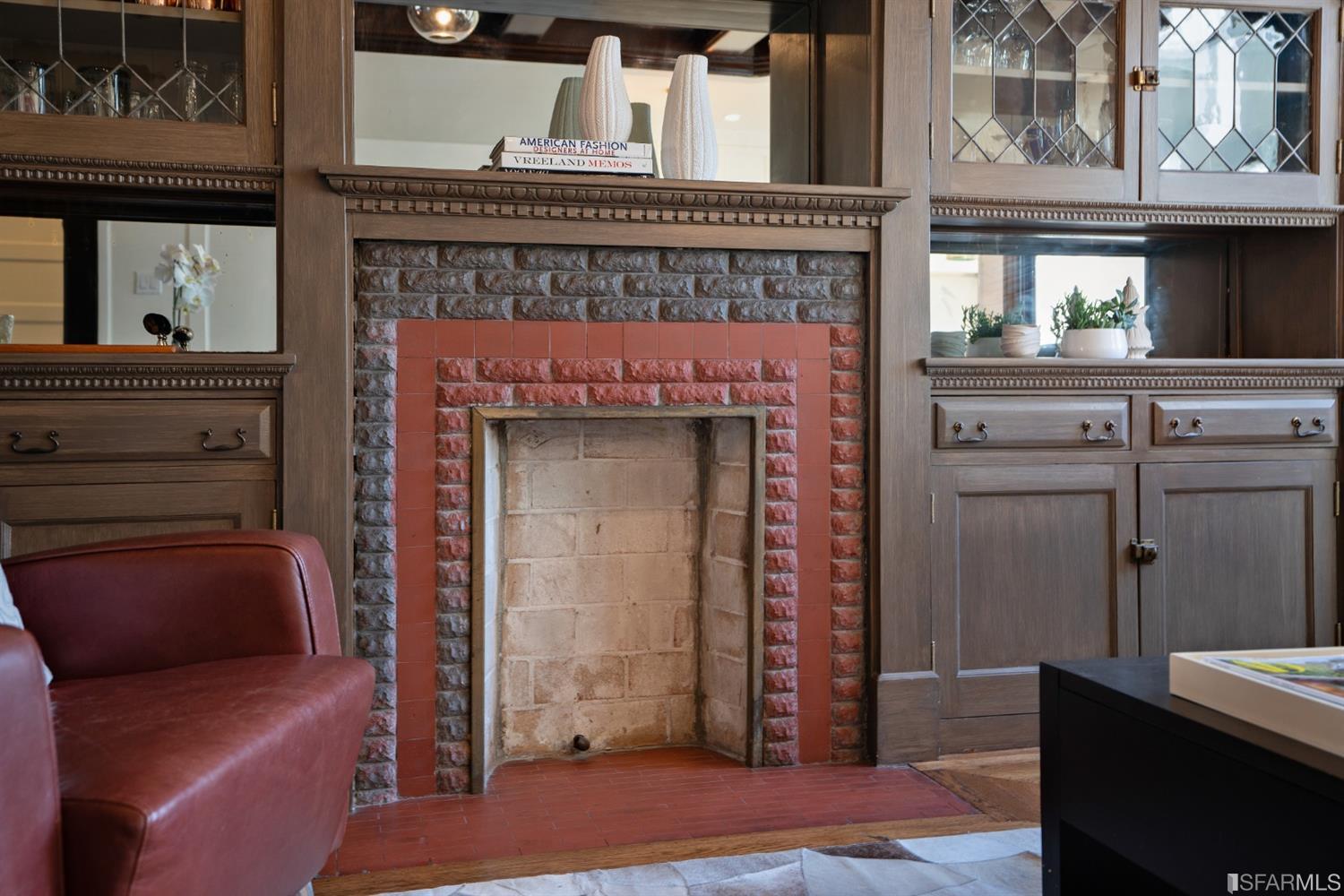 Property Photo: Close-up of the fireplace, showing brick surround and built-in cabinetry 