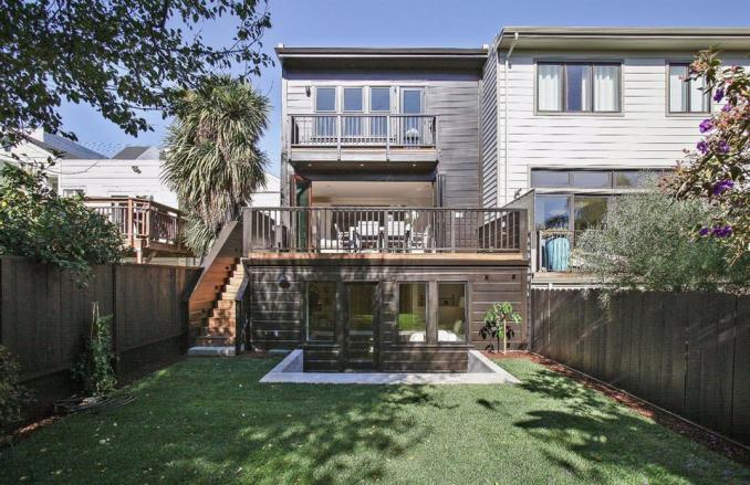 Property Thumbnail: Rear exterior view of 4069 25th Street, showing a large lawn and multiple decks