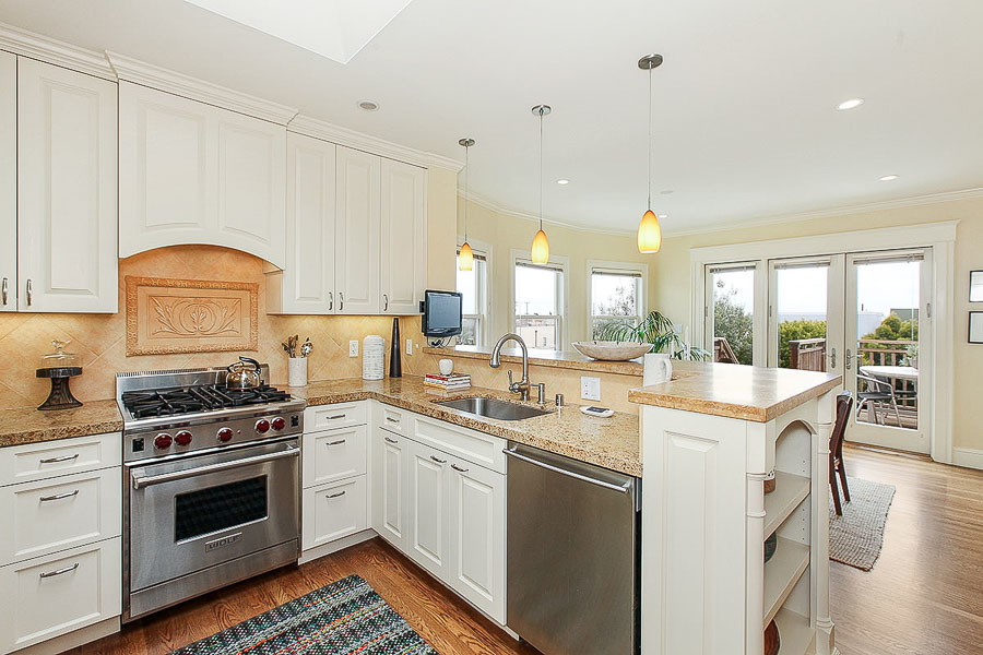 Property Photo: View of the kitchen, featuring white cabinets and wood floors