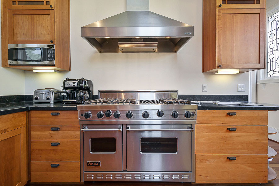 Property Photo: Close-up view of the high-end stove and wood cabinets