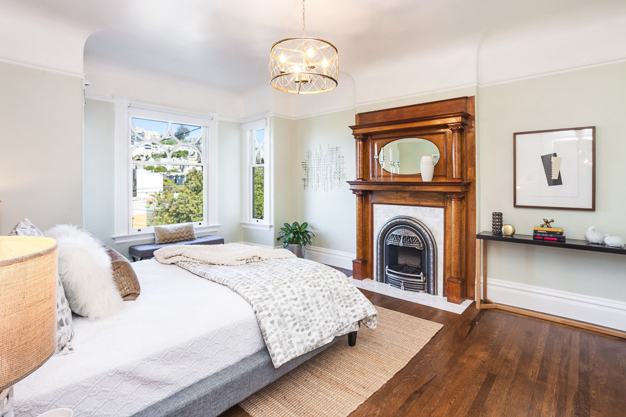 Property Photo: Bedroom with a large fireplace and wood mantle 