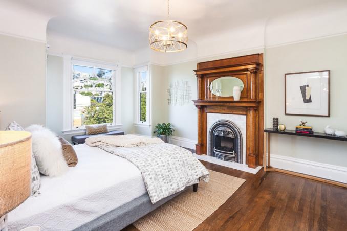 Property Thumbnail: Bedroom with a large fireplace and wood mantle 