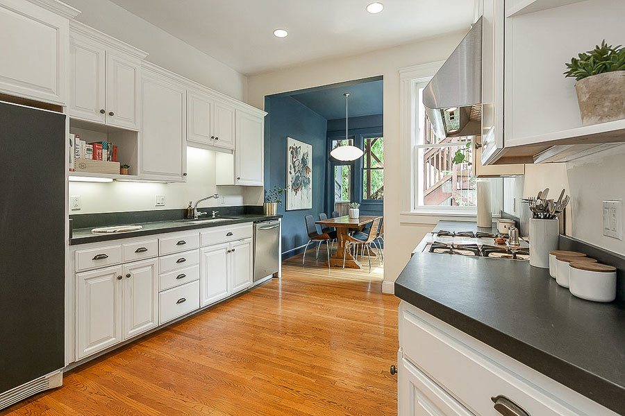 Property Photo: View of the kitchen, showing white cabinets with black counter-tops