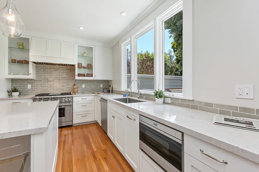 Property Photo: View of the kitchen, featuring white cabinetry and three large windows