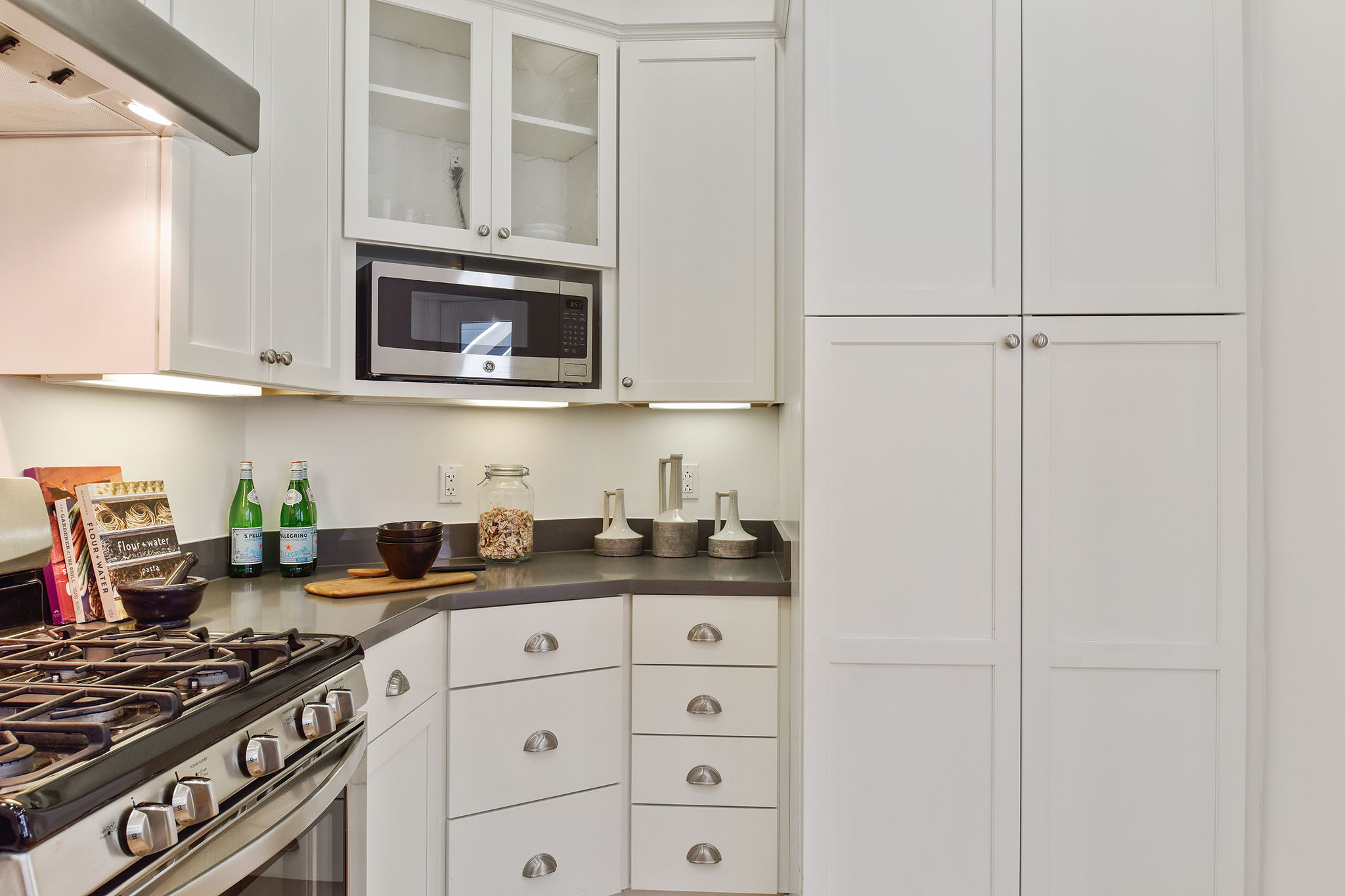 Property Photo: Kitchen, featuring a stainless stove and white cabinets