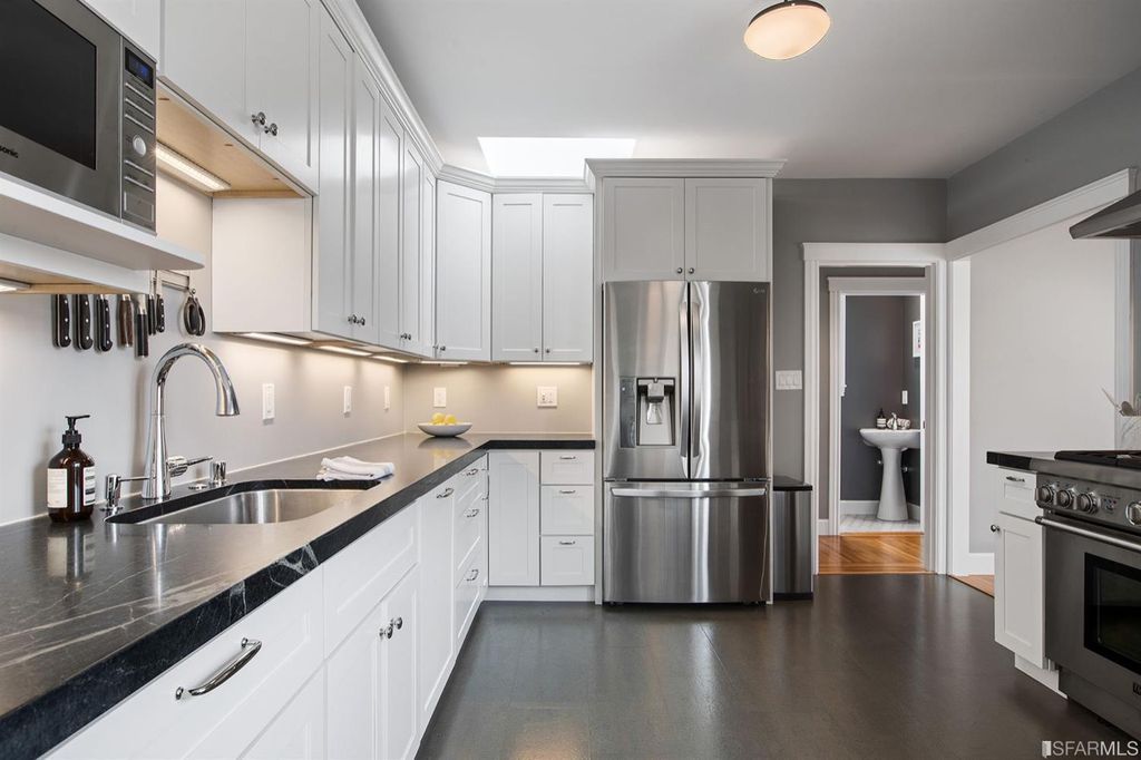Property Photo: Kitchen, featuring white cabinets with black counter-tops