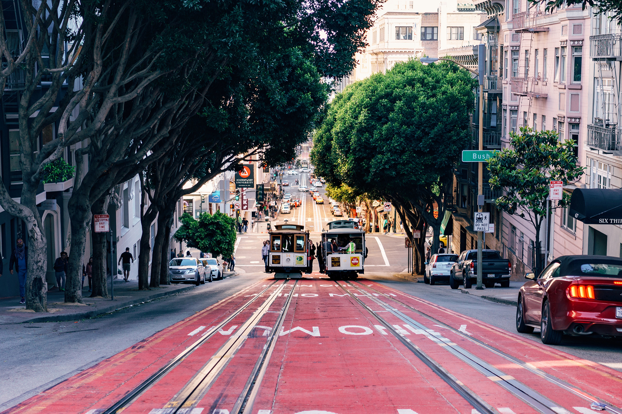 A view of two trolly cars traveling down a steep street in San Francisco